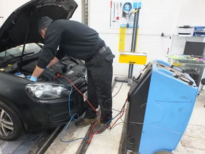 A mechanic connecting the air conditioning machine to a car