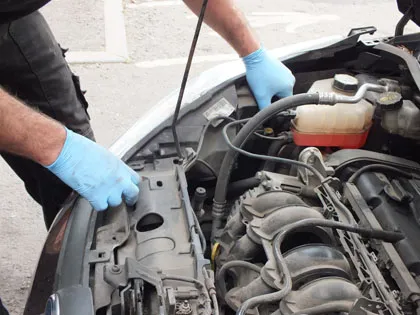 Gloved hands working on an engine, bonnet up