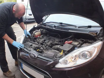 Leon Bennett checking the engine of a Ford Fiesta, bonnet up