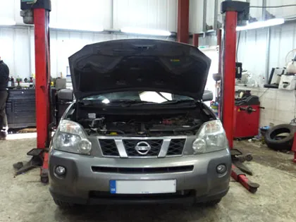 A Nissan on the lift in the workshop, bonnet up